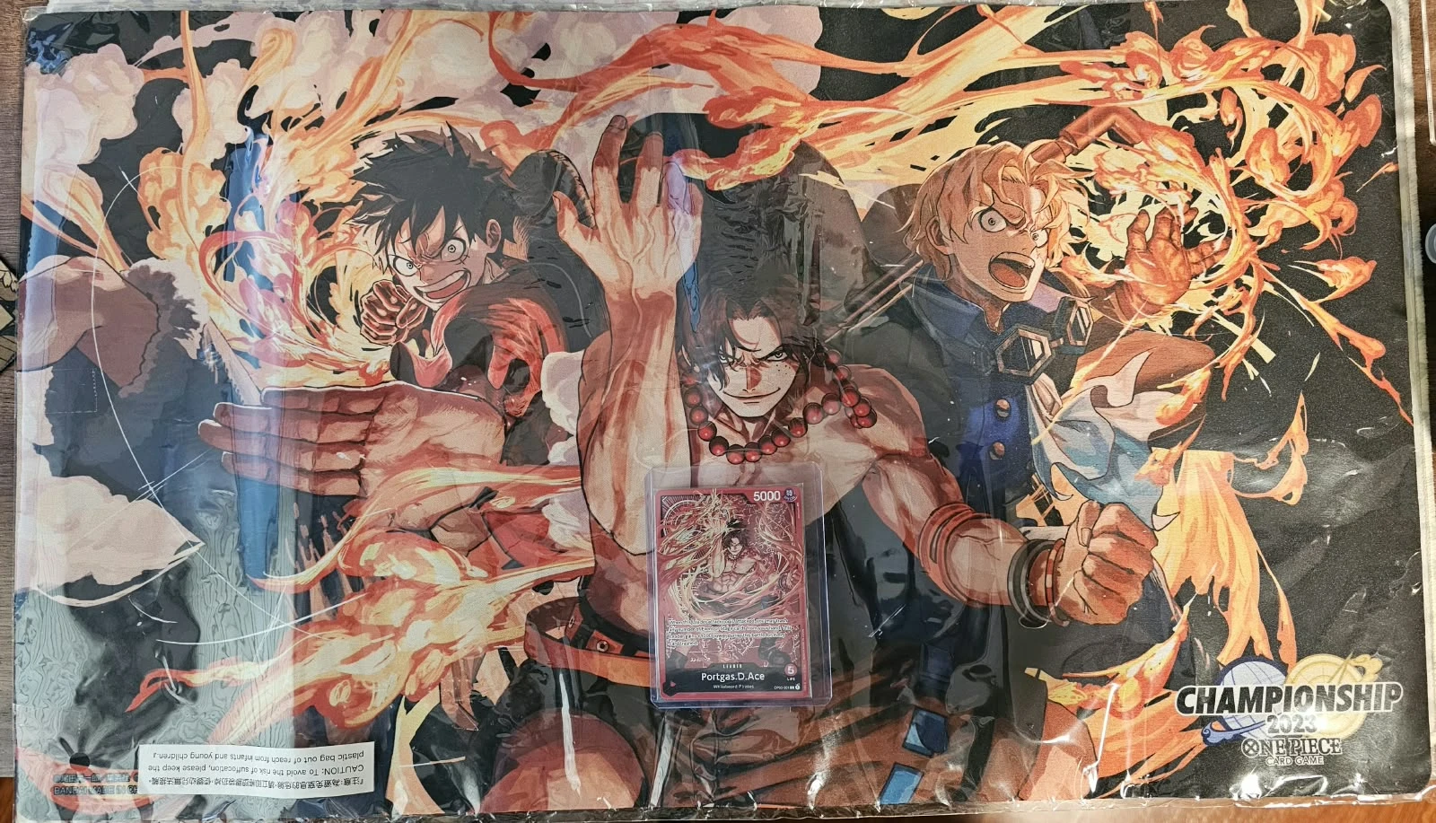 Ace/Sabo/Luffy Playmat Championship 2023 + Carta Portgas.D.Ace